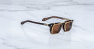 Jacques Marie Mage Moscova in Beau acetate optical frame with Gold clip-on, angled view featuring rectangular brown-tinted lenses, rich tortoiseshell acetate, signature arrowhead pins, and polished gold clip-on attachment with exposed core wire temples