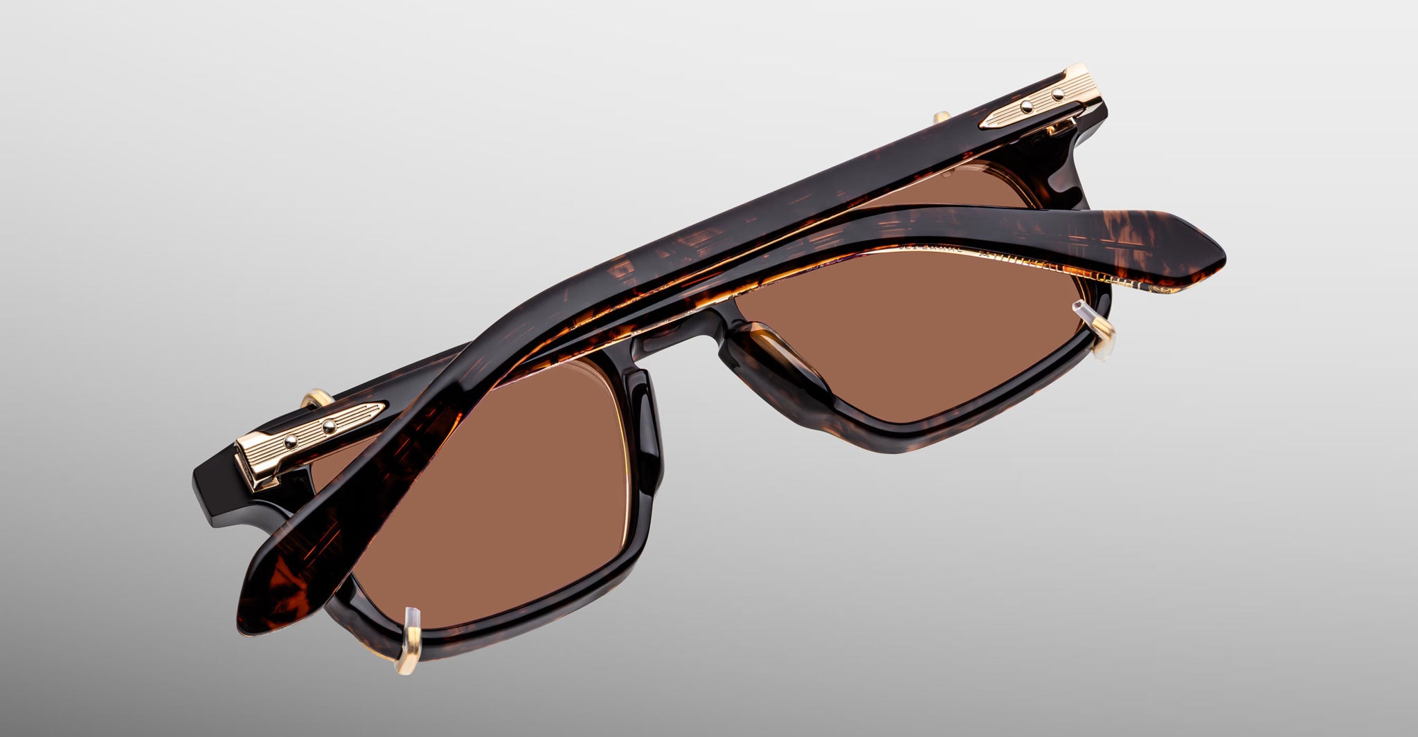 Jacques Marie Mage Moscova in Beau acetate optical frame with Gold clip-on, top-down angled view showcasing rectangular silhouette, rich tortoiseshell acetate, arrowhead front pins, gold monoblock hinges, and brown-tinted clip-on lenses