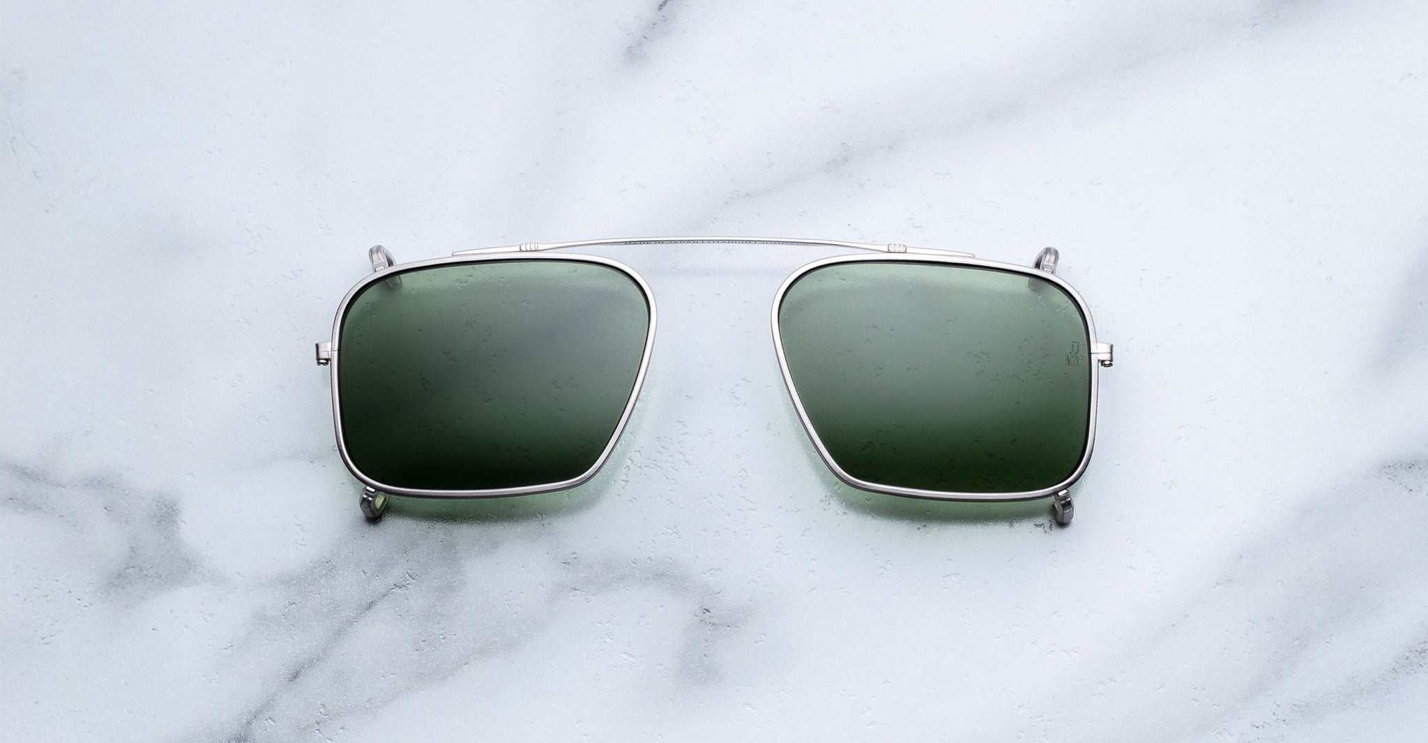 Jacques Marie Mage Moscova clip-on in Silver, front-facing view with rectangular green-tinted lenses, slim silver metal frame, and bridge-mounted clip mechanism designed to attach seamlessly to Moscova optical frames