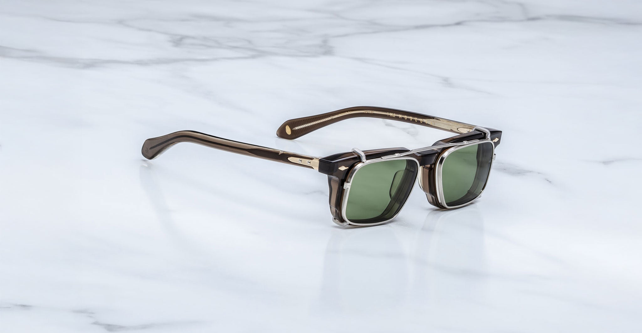 Jacques Marie Mage Moscova in London acetate optical frame with Silver clip-on, angled view featuring rectangular green-tinted lenses, translucent brown acetate, signature arrowhead pins, and slim silver clip-on attachment with exposed core wire temples