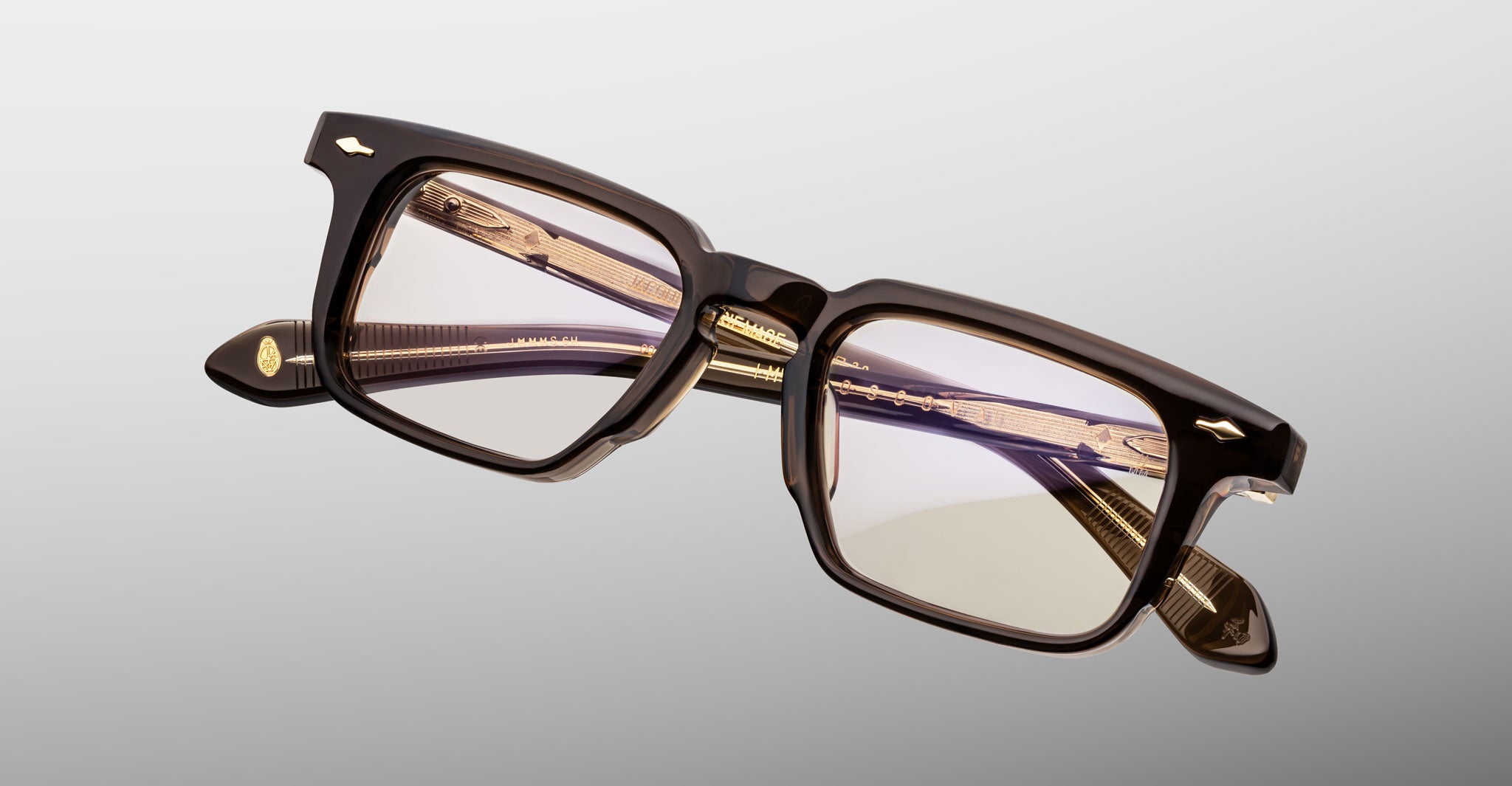 Jacques Marie Mage Moscova in London acetate optical frame, angled view highlighting rectangular lenses, sculpted translucent brown front, signature arrowhead pins, and exposed core wire temples with warm tonal detailing
