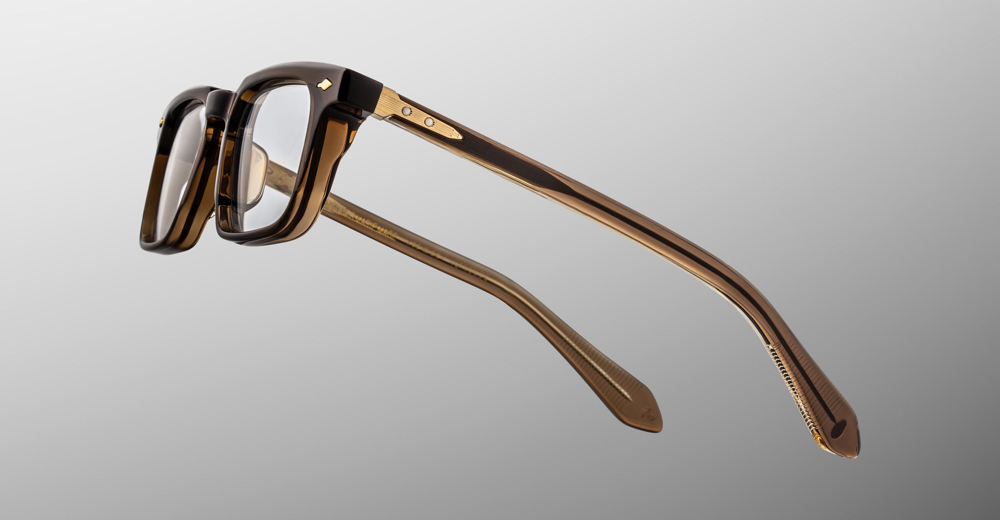 Jacques Marie Mage Moscova in London acetate optical frame, side profile highlighting sculpted translucent brown acetate, gold hardware at the hinge, signature arrowhead pin, and tapered temples with exposed core wire and warm tonal interior detailing