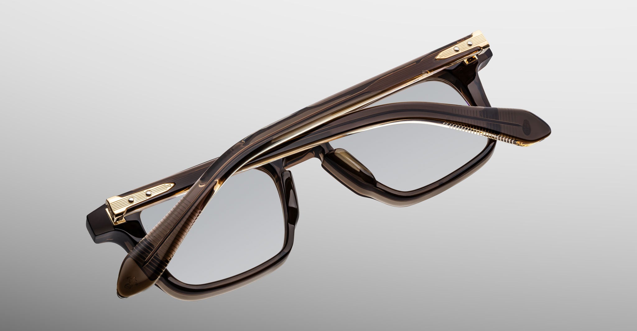 Jacques Marie Mage Moscova in London acetate optical frame, top-down angled view showcasing rectangular silhouette, translucent brown acetate, arrowhead front pins, and gold monoblock hinges with sculpted temples