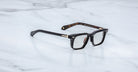 Jacques Marie Mage Moscova in Noir 15 acetate optical frame with rectangular lenses, sculpted black front, gold arrowhead pins, and exposed metal core temples with tortoiseshell interior detailing