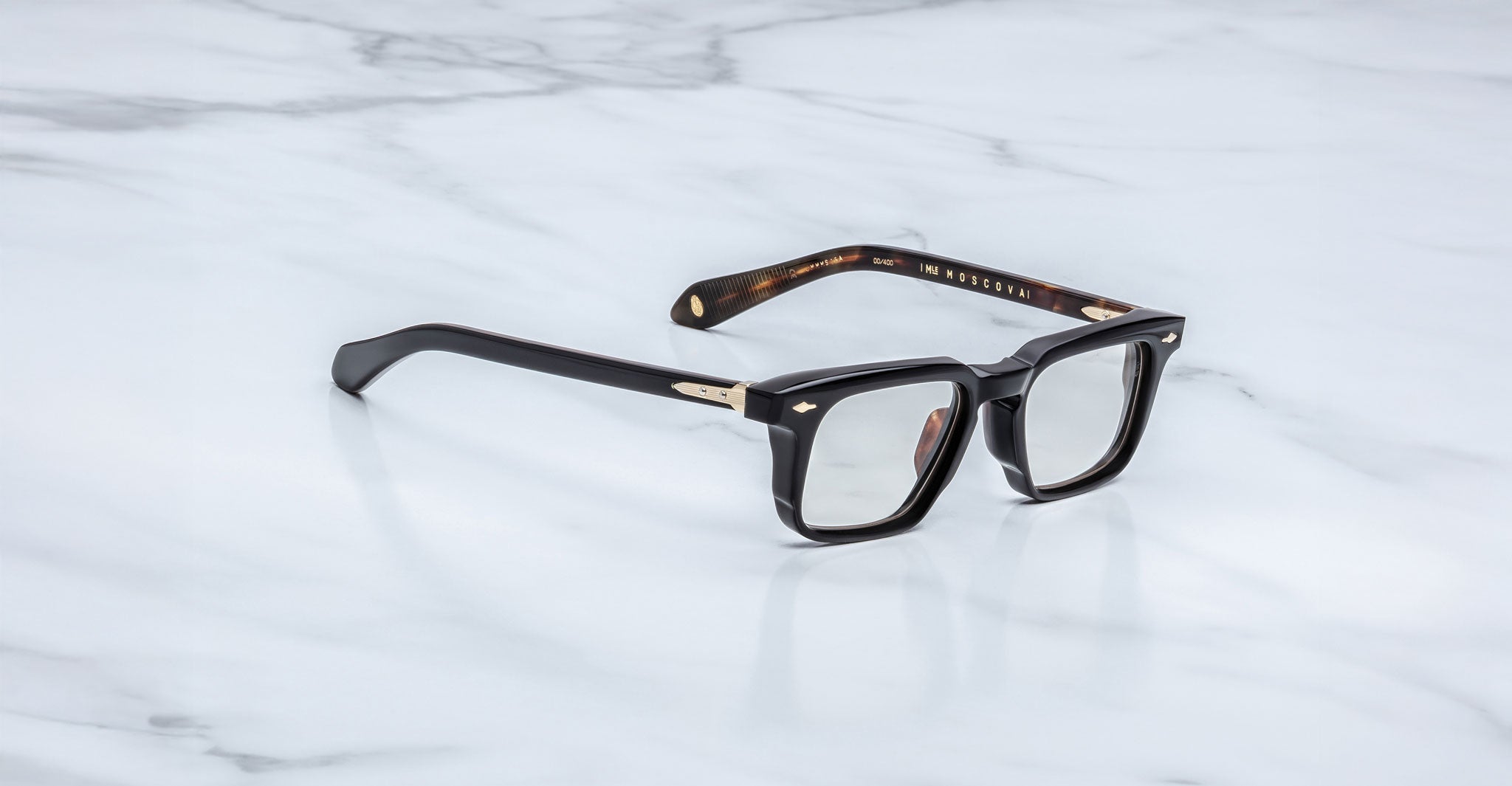 Jacques Marie Mage Moscova in Noir 15 acetate optical frame with rectangular lenses, sculpted black front, gold arrowhead pins, and exposed metal core temples with tortoiseshell interior detailing
