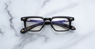 Jacques Marie Mage Moscova in Noir 15 acetate optical frame, front-facing view with rectangular lenses, polished black acetate, signature arrowhead pins, and visible core wire temples with tortoiseshell interior detailing