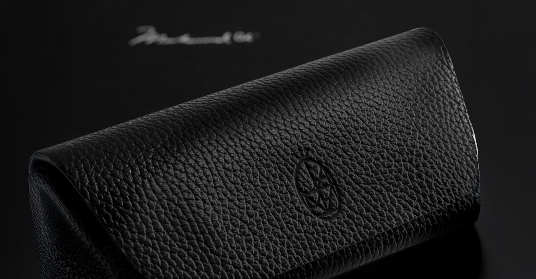 Jacques Marie Mage Kinshasa eyeglasses case, black textured leather with embossed logo, top view.