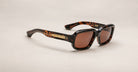 Jacques Marie Mage Nakahira tortoiseshell sunglasses with thick square frames, brown lenses, and gold temple detailing, displayed on a light neutral background.
