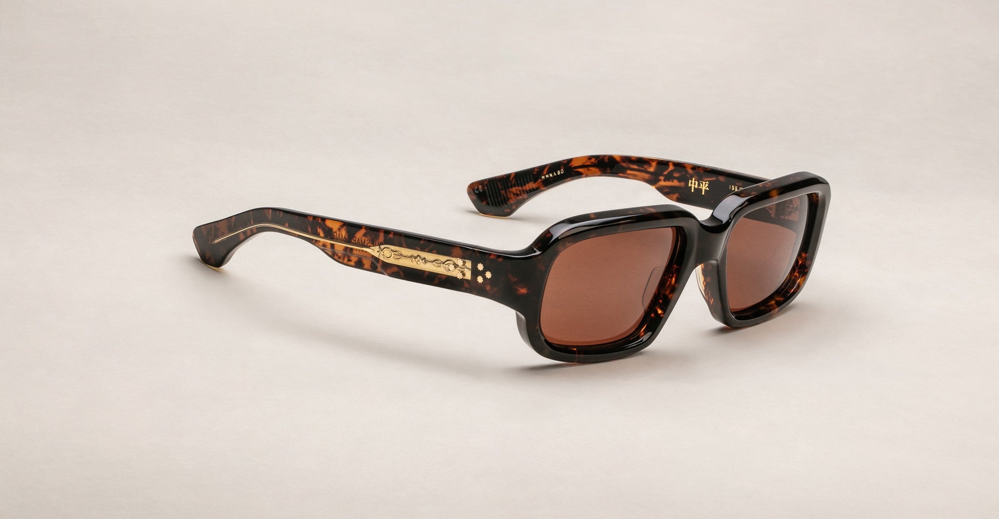 Jacques Marie Mage Nakahira tortoiseshell sunglasses with thick square frames, brown lenses, and gold temple detailing, displayed on a light neutral background.