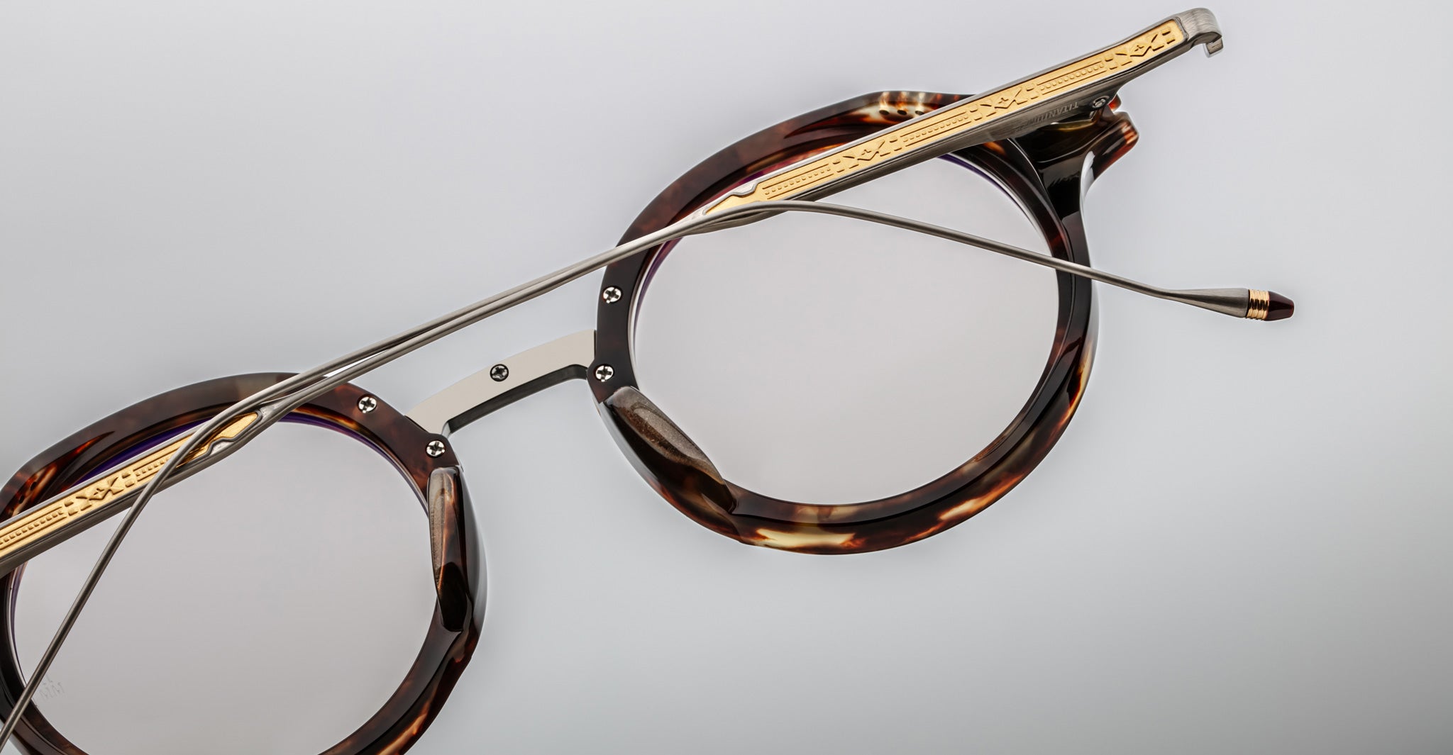 Jacques Marie Mage Norman round tortoiseshell eyeglasses with gold accents and slim metal arms, shown from a front angle.
