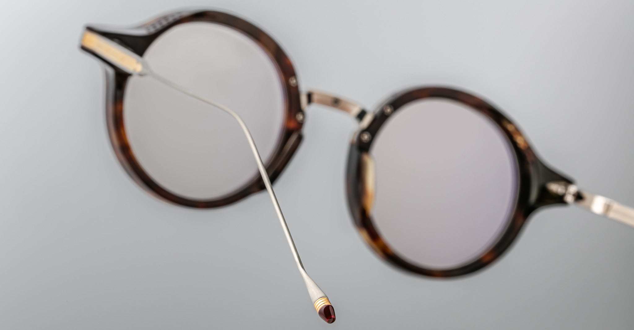 Jacques Marie Mage Norman eyeglasses, round tortoiseshell frames with thin metal arms and red tips, front view.