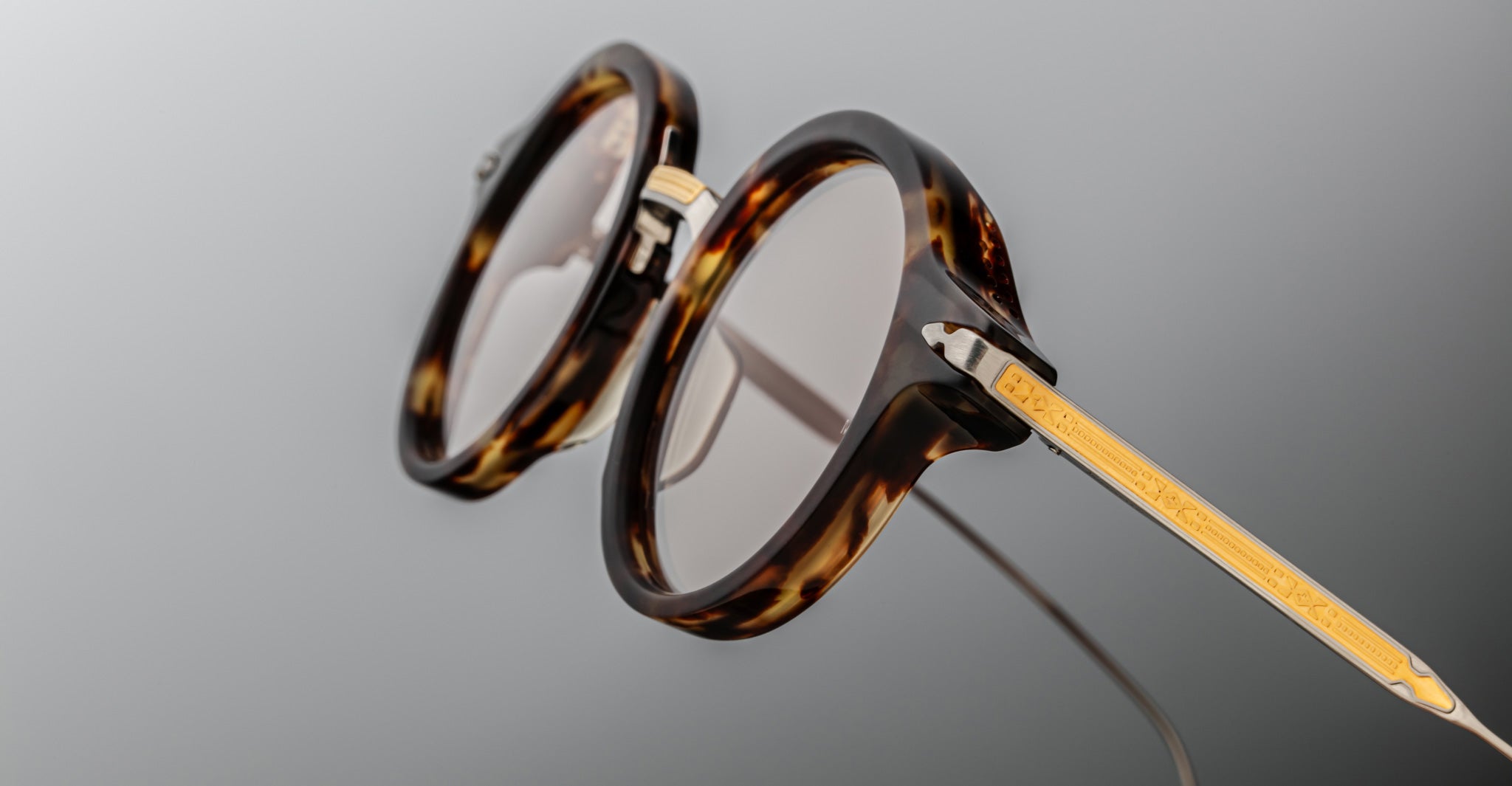 Close-up of Jacques Marie Mage Norman round eyeglasses, gold temples visible, front angle.