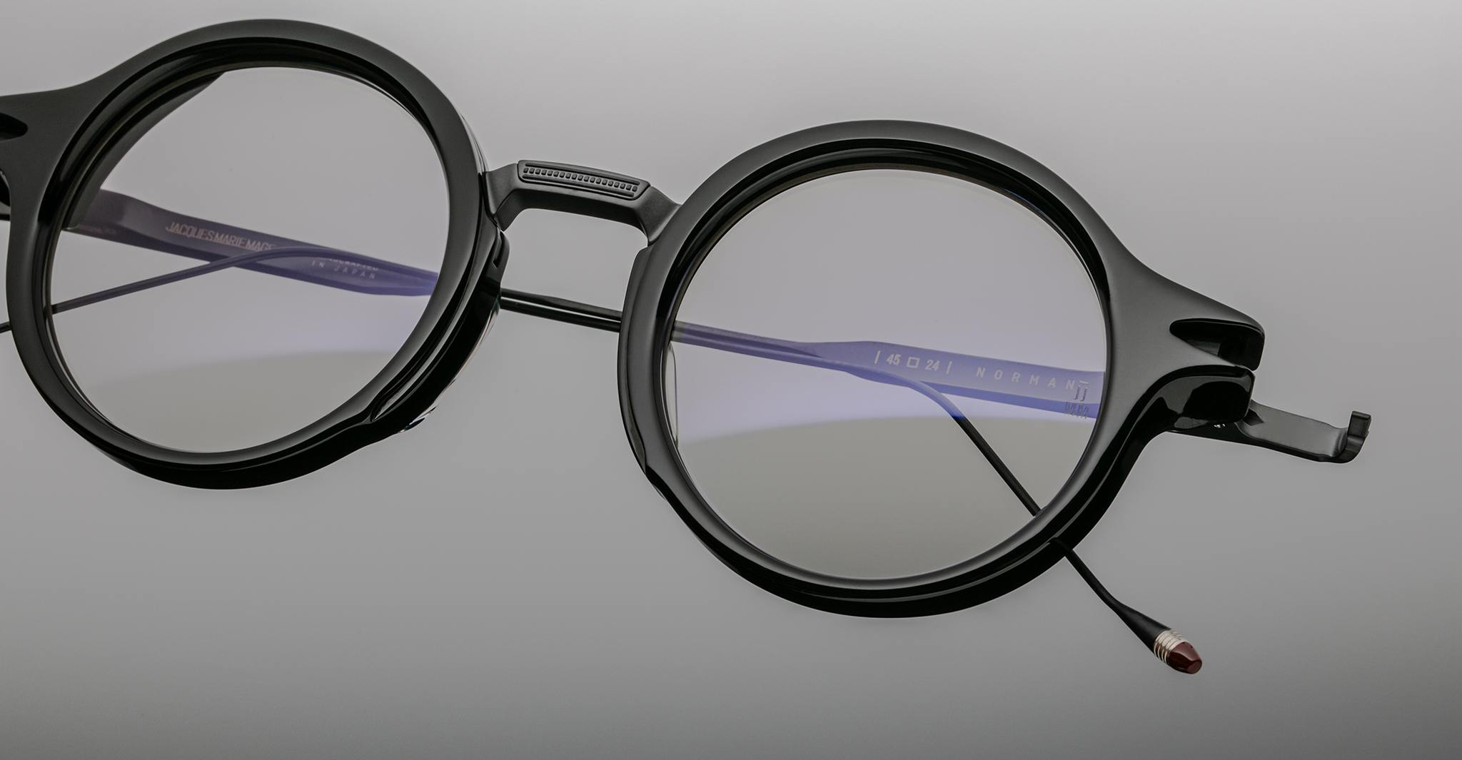 Jacques Marie Mage Norman round black eyeglasses with thick frames and one detached temple arm, front angle view.
