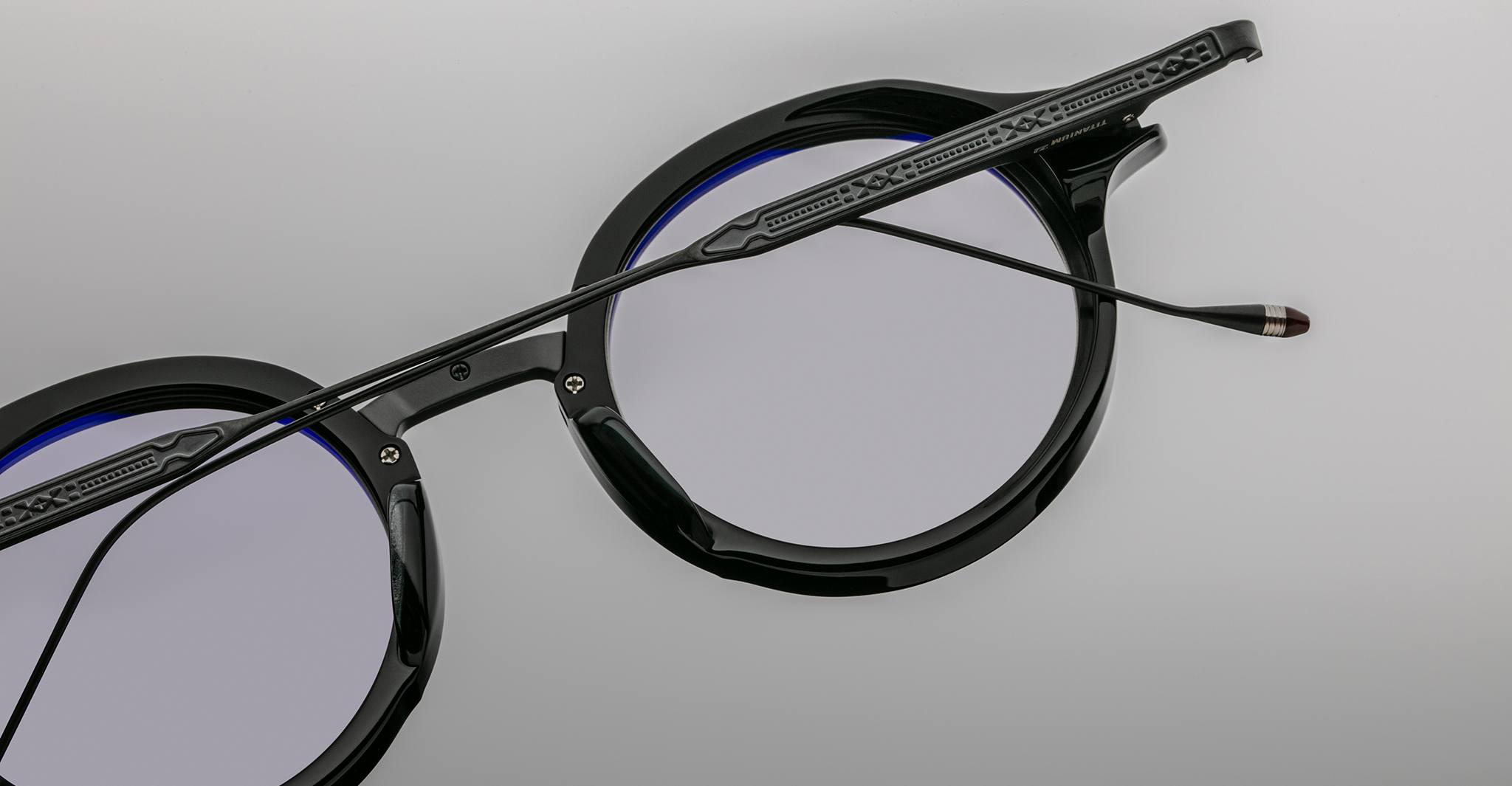 Close-up of Jacques Marie Mage Norman black round eyeglasses with blue-tinted, anti-glare lenses, front angle.