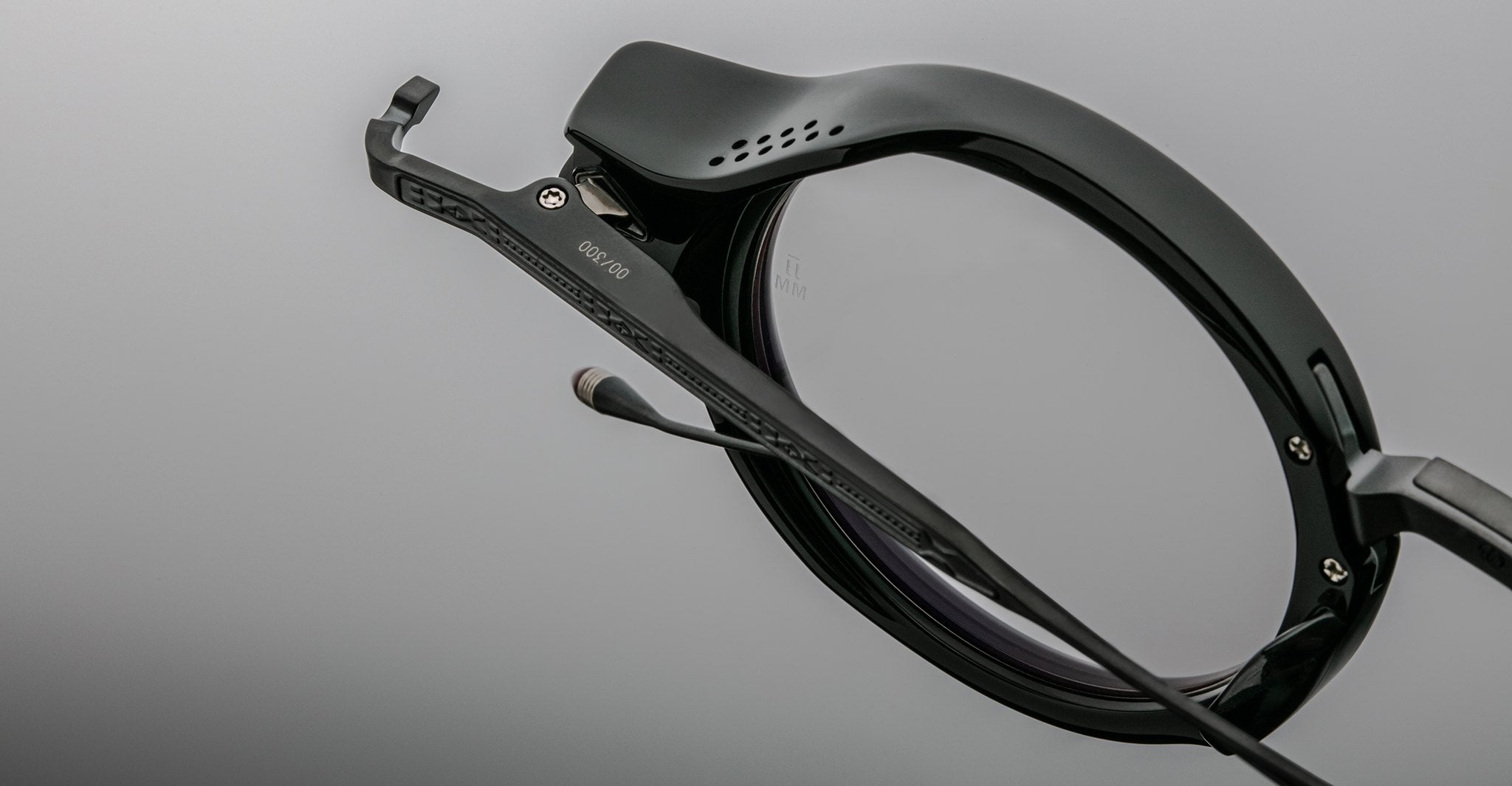 Close-up of Jacques Marie Mage Norman black smart eyeglasses, showing Bluetooth mic and speaker on the temple.