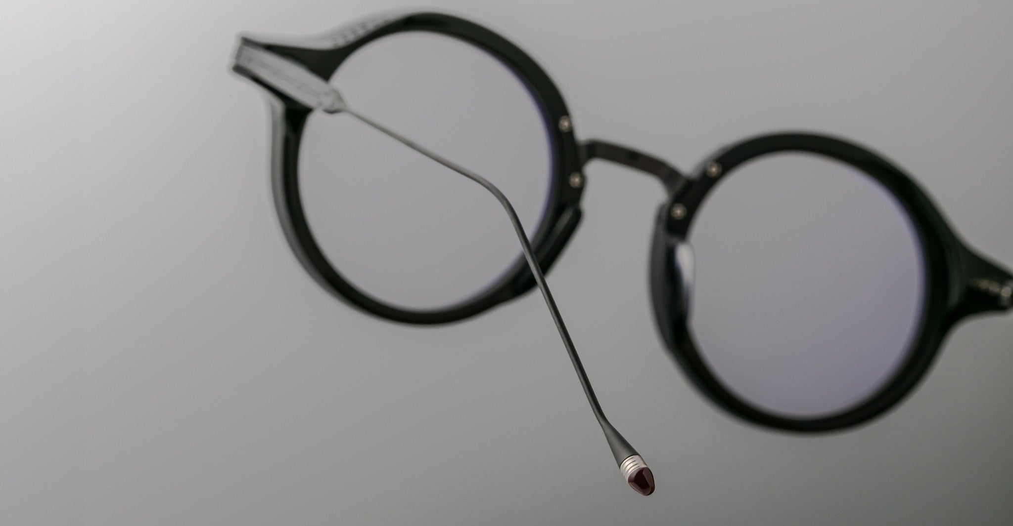 Close-up of Jacques Marie Mage Norman black round eyeglasses, side angle showing one temple arm extended.