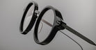 Close-up of Jacques Marie Mage Norman black round eyeglasses with clear lenses, front view.