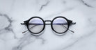 Jacques Marie Mage Norman round black eyeglasses with clear lenses, front view.