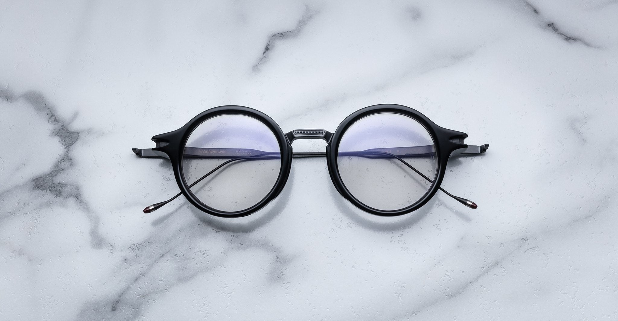Jacques Marie Mage Norman round black eyeglasses with clear lenses, front view.