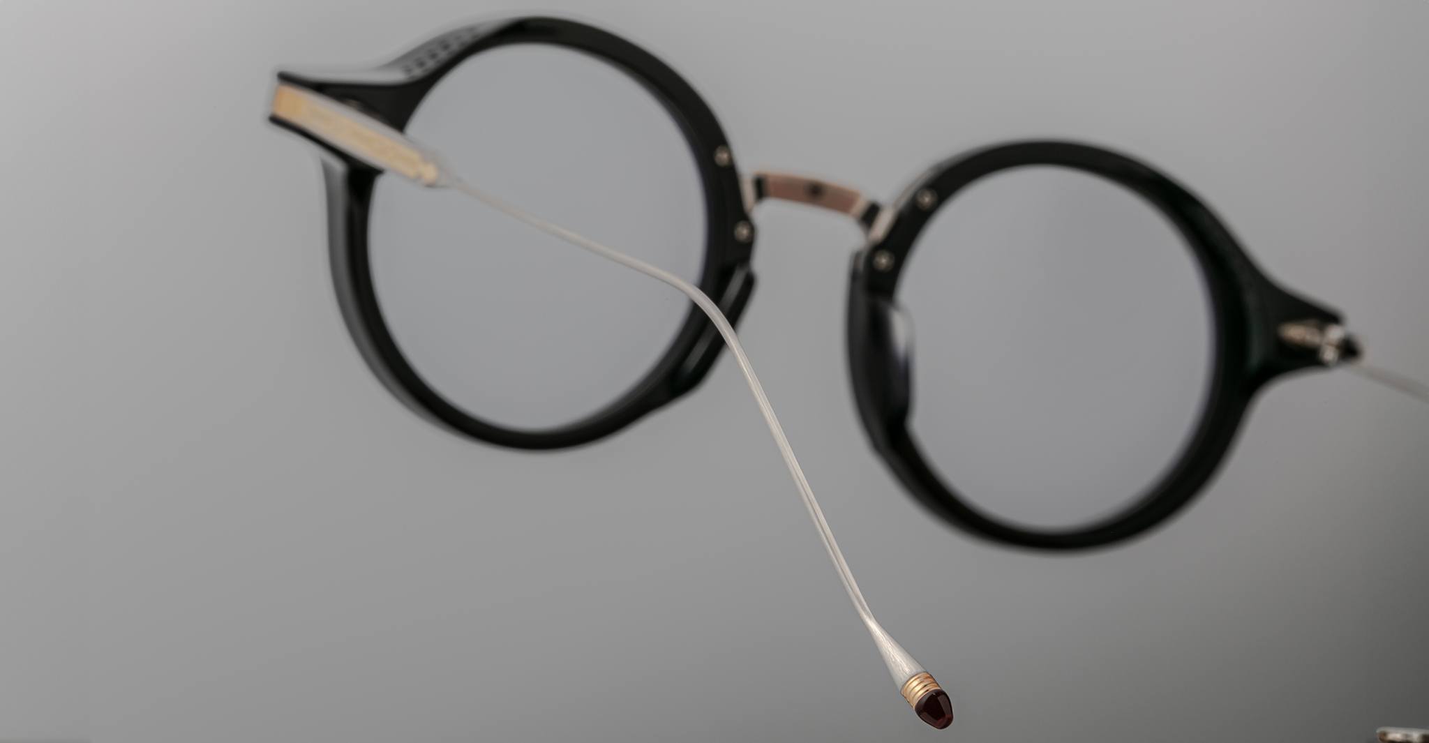 Jacques Marie Mage Norman eyeglasses, round black frames with a slim silver nose bridge, front view.