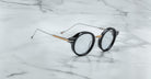 Jacques Marie Mage Norman eyeglasses with round black rims and thin metal arms, front angle.