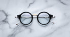 Jacques Marie Mage Norman black-rimmed eyeglasses with clear lenses, top-down view.