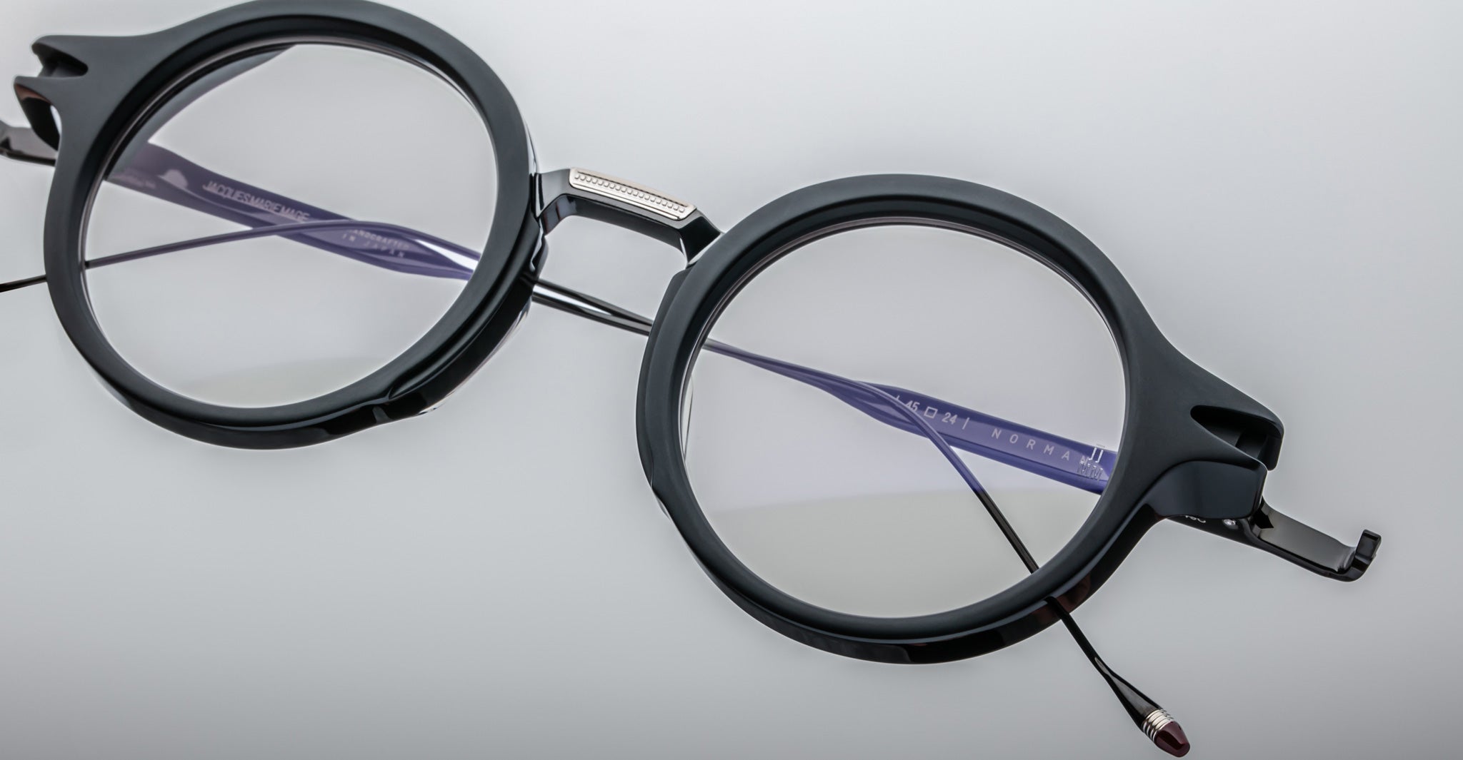Jacques Marie Mage Norman round black eyeglasses with clear lenses and thin temples shown from above.