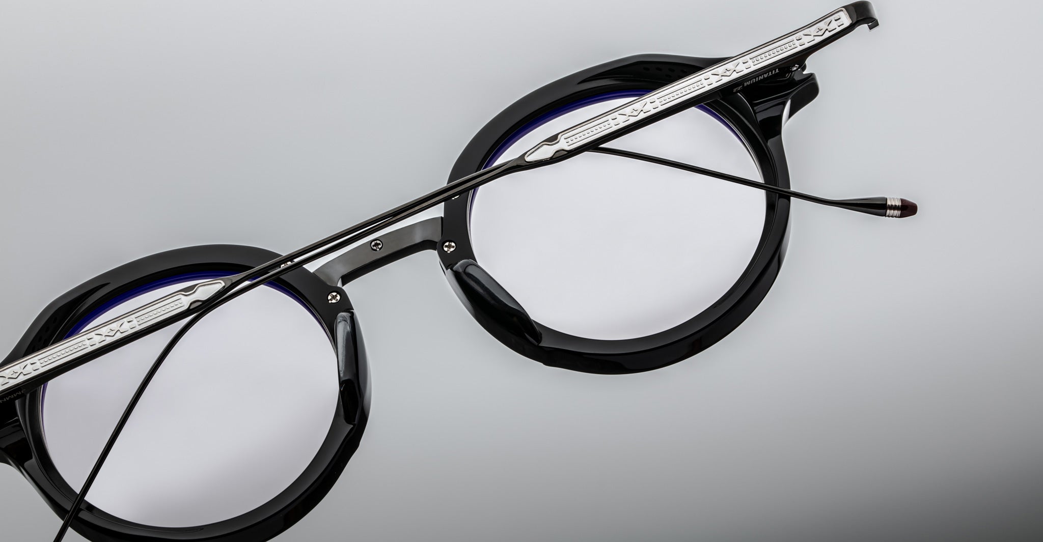 Close-up of Jacques Marie Mage Norman round eyeglasses in black with silver arms, showing front and side details.