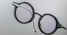 Close-up of Jacques Marie Mage Norman black round eyeglasses, side view showing one extended arm.