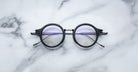 Jacques Marie Mage Norman black eyeglasses with clear lenses, shown from above.