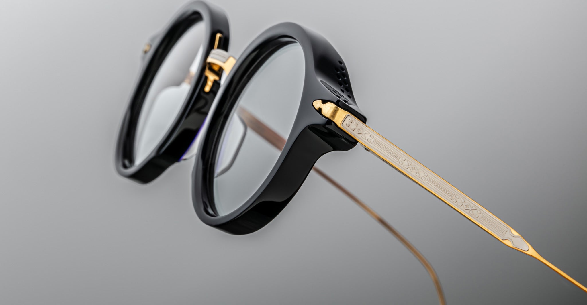 Close-up of Jacques Marie Mage Norman round eyeglasses, black frame with gold temples, front angle.
