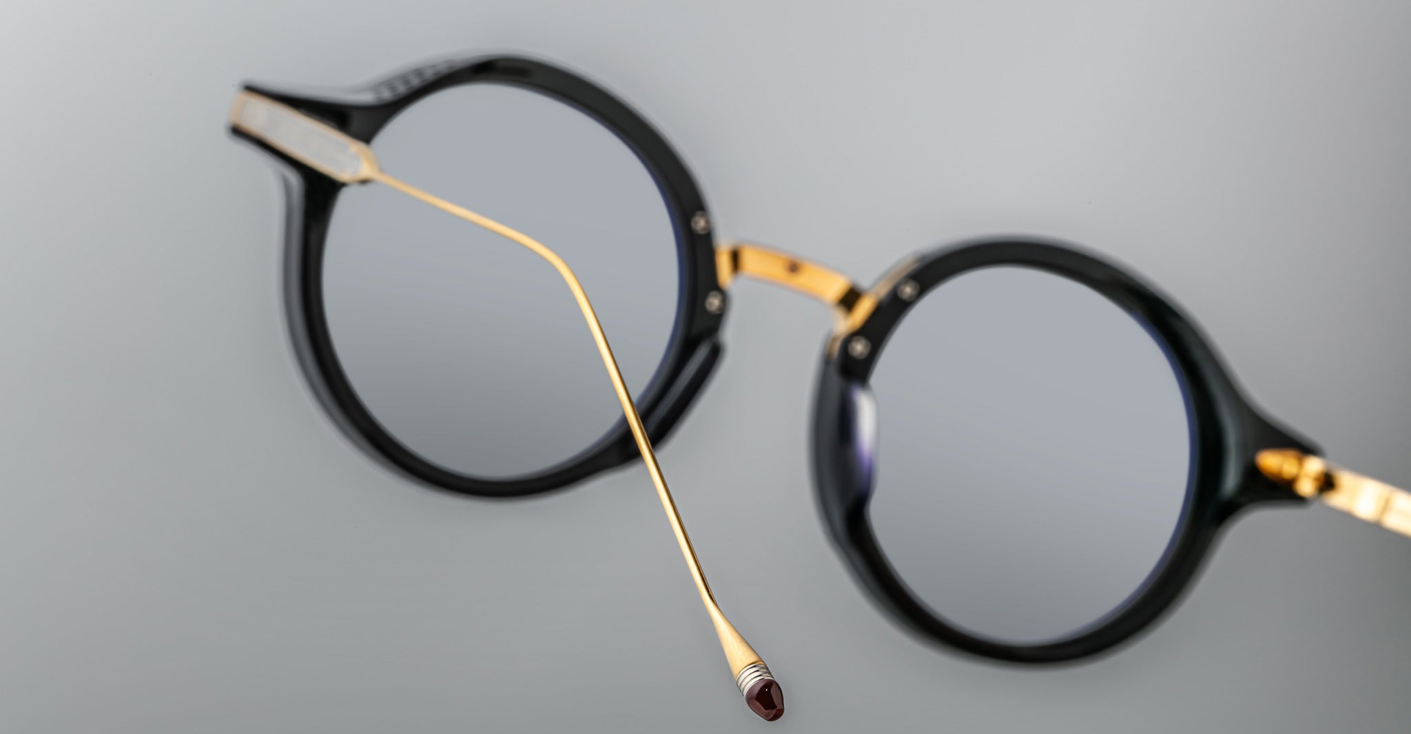 Jacques Marie Mage Norman round black eyeglasses with gold temples, side view showing end tip detail.