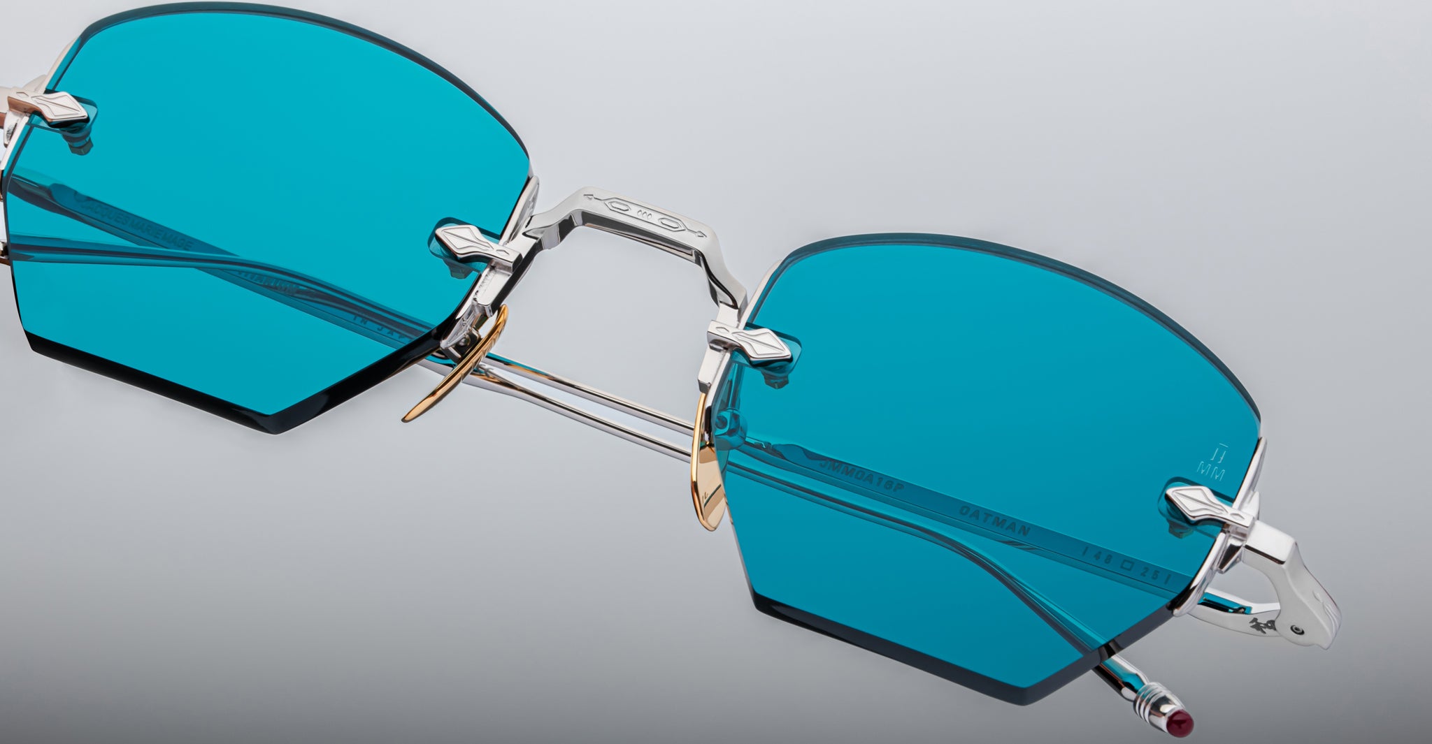 Close-up of the Jacques Marie Mage Oatman sunglasses—hexagonal, rimless frames with blue lenses, silver metal bridge, and gold nose pads—highlighting the refined craftsmanship of handmade Japanese eyewear by Jacques Marie Mage.