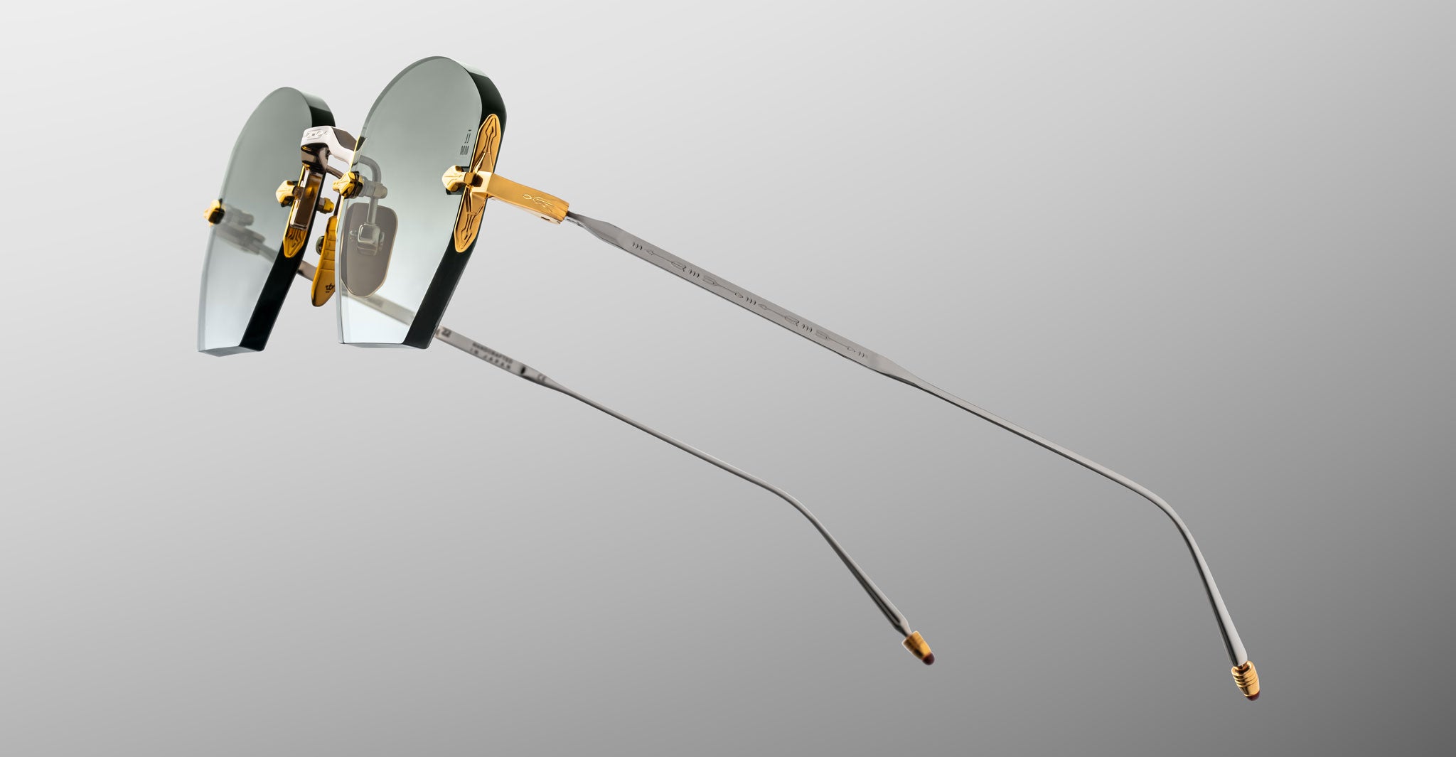 BrandName ModelName rimless eyeglasses, gold and silver metal arms, side view.