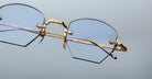 Close-up of Jacques Marie Mage Oatman eyeglasses with gold metal frames and blue-tinted geometric lenses, inspired by handmade Japanese eyewear, shown against a plain background.