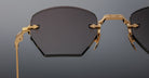 Close-up of Jacques Marie Mage Oatman sunglasses: luxury hexagonal rimless dark lenses with a gold metal frame, detailed hinge, and geometric design. Exquisite handmade Japanese eyewear by Jacques Marie Mage against a plain background.