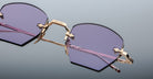 Close-up of Jacques Marie Mage Oatman gold-rimmed, hexagonal rimless sunglasses with purple-tinted lenses on a light gray background, highlighting the brand's exquisite handmade Japanese craftsmanship.