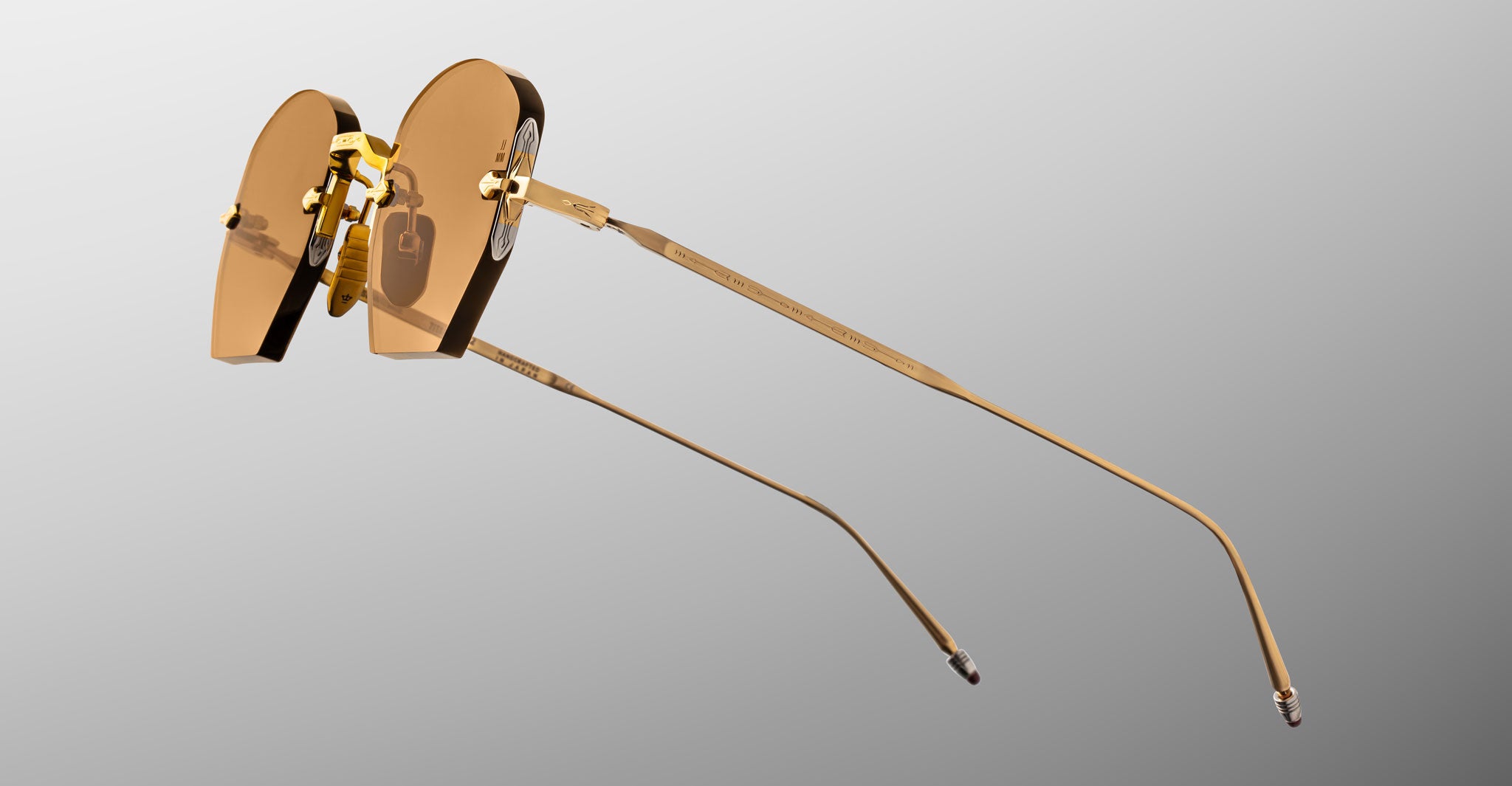 Jacques Marie Mage Oatman in Suntan gold-rimmed rimless sunglasses with brown-tinted lenses, side view.