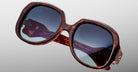 Close-up of oversized, square-shaped Jacques Marie Mage Ocean Child sunglasses in tortoiseshell with blue-tinted lenses, featuring engraved arm text reflecting light, set against a smooth light gray gradient background.