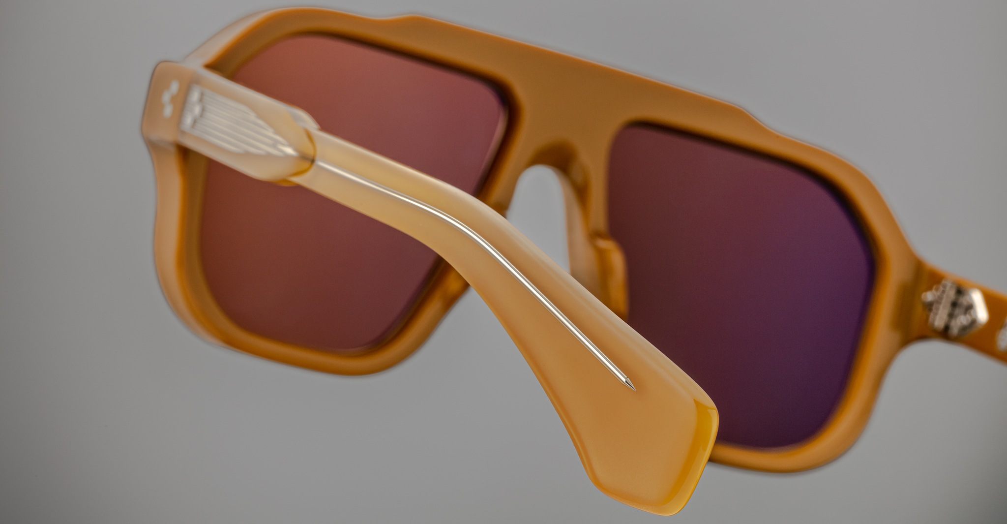 A close-up of Jacques Marie Mage Octavian sunglasses featuring brown color, oversized design, wide temples, and tinted lenses set against a neutral background.