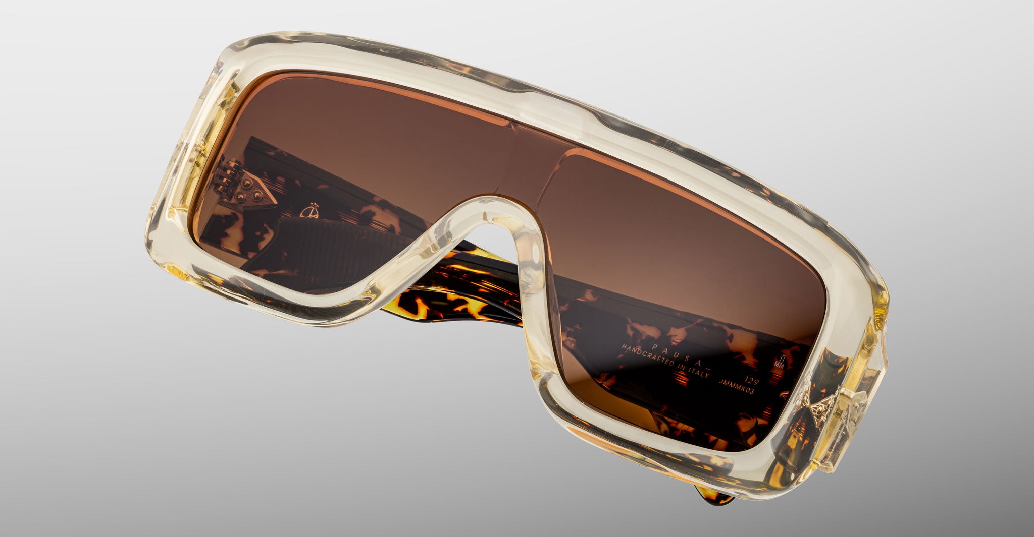 Close-up of Jacques Marie Mage Pausa sunglasses, oversized rectangular style with brown lenses and clear chunky tortoiseshell frame.