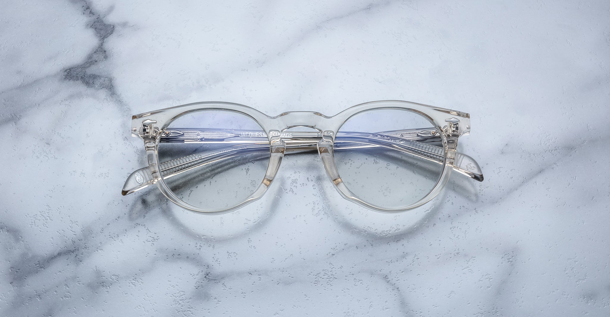 Jacques Marie Mage Percier eyeglasses with clear round frames and silver temples, shown from a front angle.