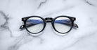Jacques Marie Mage Percier black round eyeglasses with blue arms, front view.
