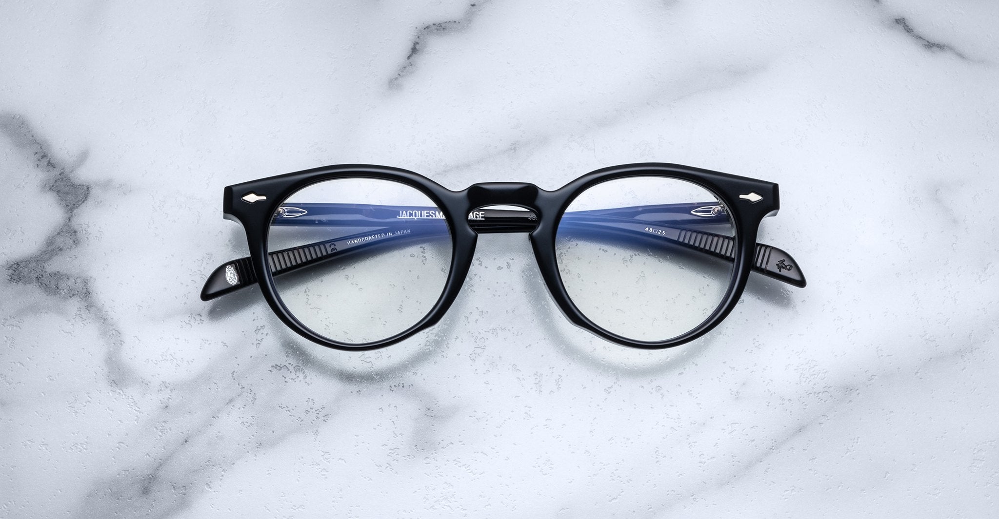 Jacques Marie Mage Percier black round eyeglasses with blue arms, front view.