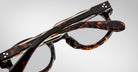 A close-up of two Jacques Marie Mage Petrus tortoiseshell eyeglasses stacked together, highlighting their frames and clear lenses at an angle on a plain light gray background.