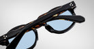 A close-up of folded Jacques Marie Mage Petrus sunglasses in tortoiseshell with light blue lenses, showing the top and sides of the frames against a plain white background.