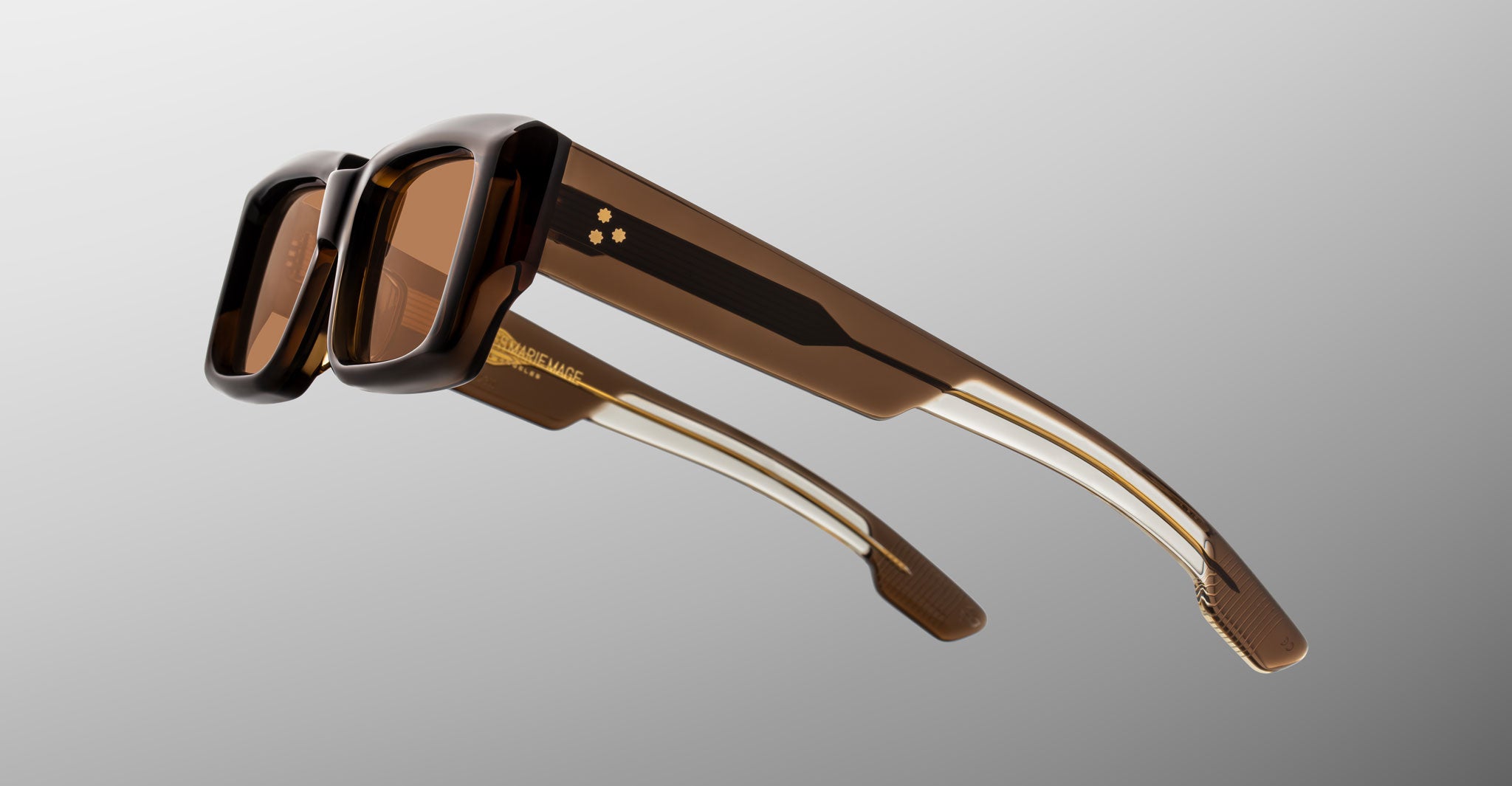 Jacques Marie Mage Quant in London, rectangular translucent brown acetate sunglasses shown from a rear side angle, highlighting wide temples with signature metal inlay, sculpted temple tips, and warm brown tinted lenses.