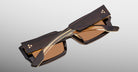Jacques Marie Mage Quant in London, rectangular translucent brown acetate sunglasses shown from an angled top view, highlighting wide temples with signature metal inlay, bold sculpted rims, and warm brown tinted lenses.