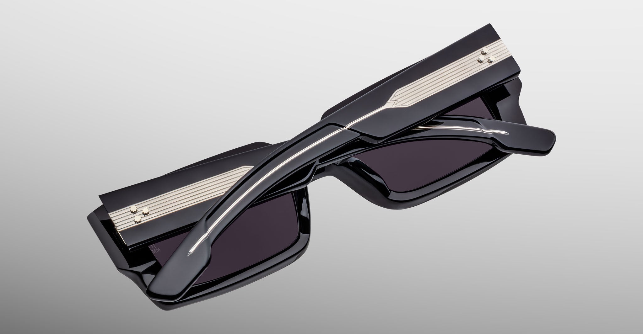 Jacques Marie Mage Quant in Shadow, rectangular black acetate sunglasses shown from an angled top view, highlighting wide temples with signature metal inlay, bold sculpted rims, and dark tinted lenses.
