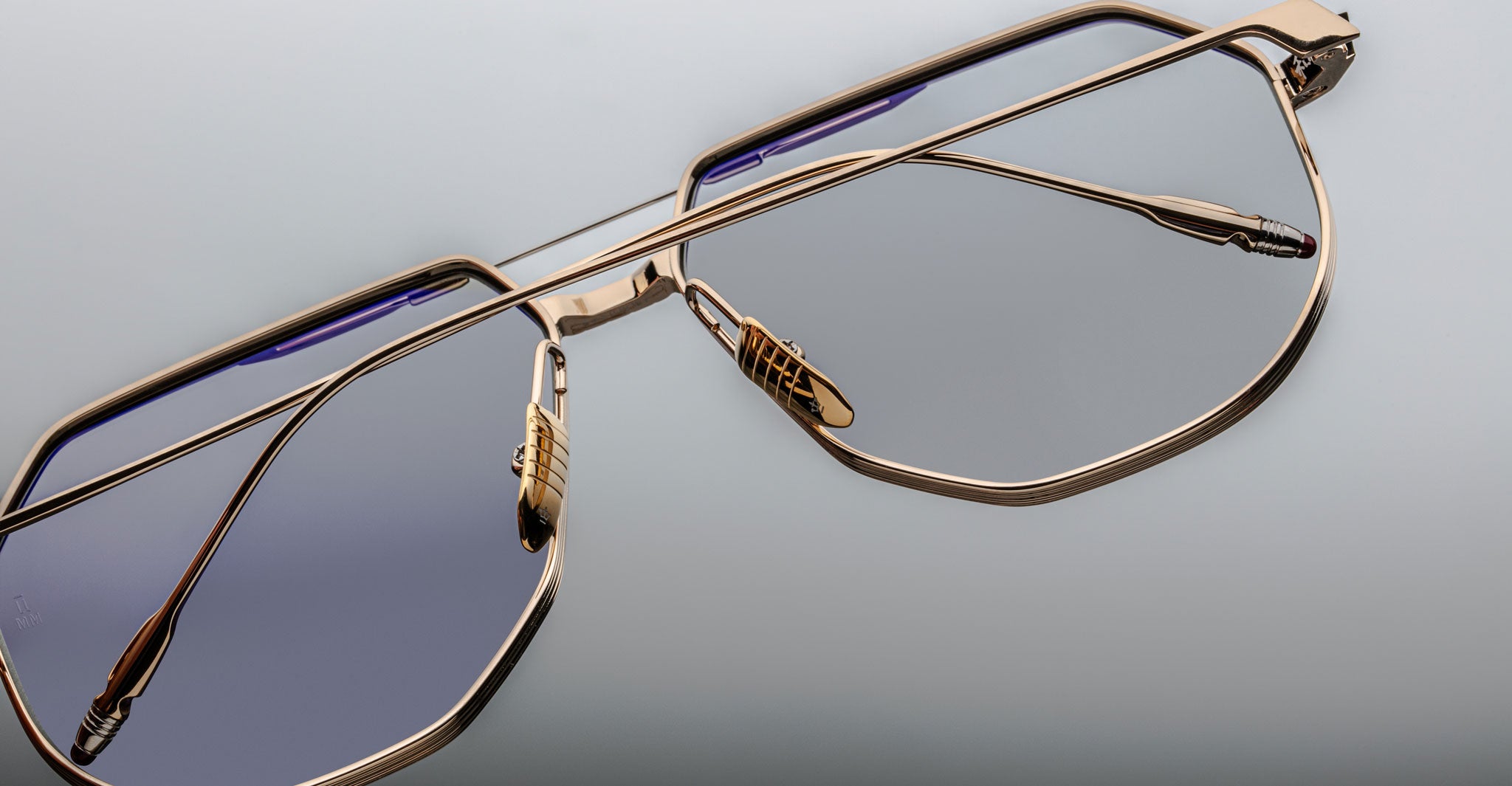 Close-up of Jacques Marie Mage Reynold eyeglasses featuring a thin titanium frame and slightly tinted lenses, displayed against a plain neutral background.